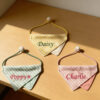 A top-down view of three personalized striped pet bandanas with adjustable drawstrings and custom embroidered names Daisy, Poppy, and Charlie